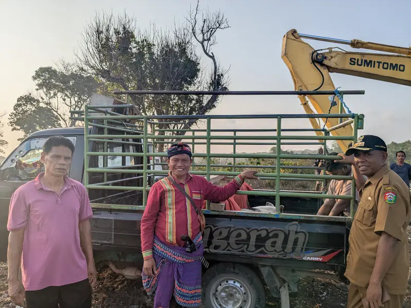 Les anciens et un représentant des autorités sur le terrain le jour de la cérémonie, devant un pick-up et la pelleteuse