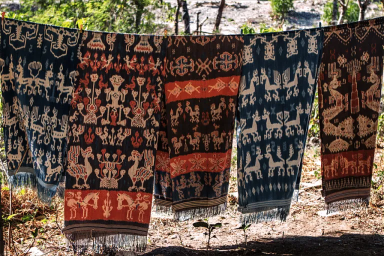 Sumba ikat cloths with horse and ancestor motifs hanging to dry outdoors.