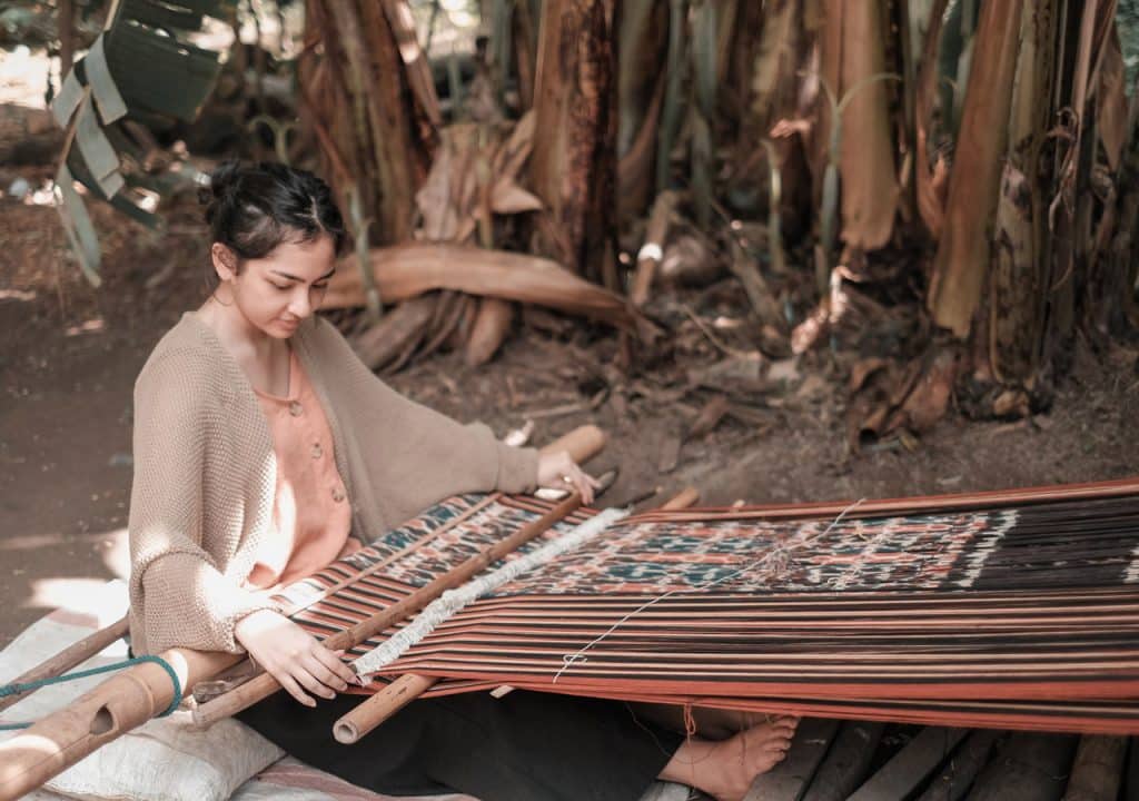 A young woman weaving ikat fabric on a backstrap loom in Sumba.